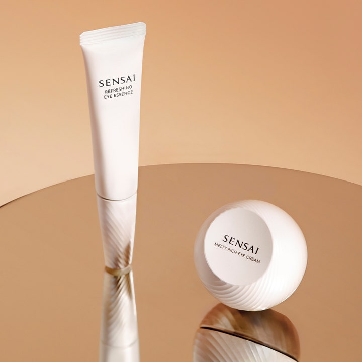 Sensai Refresh Eye Essence Refill 20 ml japanskt ögonserum i vit tub bredvid rund burk på guldreflekterande yta