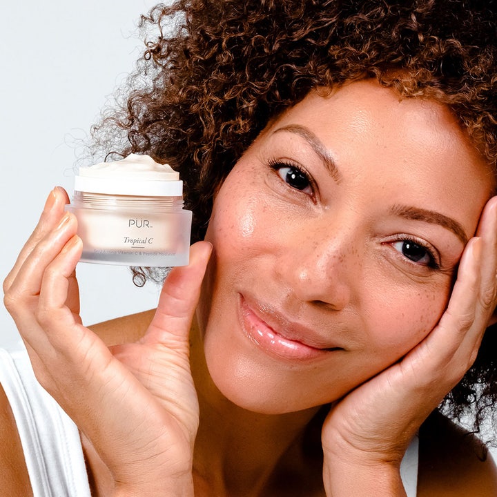 PÜR Tropical C Brightening Vitamin C & Peptide Moisturizer 50 ml lystergivande peptid ansiktskräm som hålls av en kvinna.
