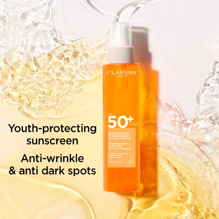Clarins Glowing Sun Care Mist SPF50+ 150 ml icke-kladdig solspray kropp mot mörka fläckar i orange flaska med vattenstänk.
