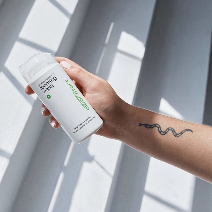 Dermalogica Clear Start Breakout Clearing Foaming Wash rengöring med salicylsyra i vit flaska hålls i en tatuerad hand