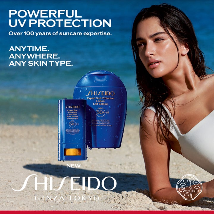 Shiseido Global Sun Care Clear Stick 20 g solskydd med SPF 50 i en strandmiljö med kvinna vid blått hav.