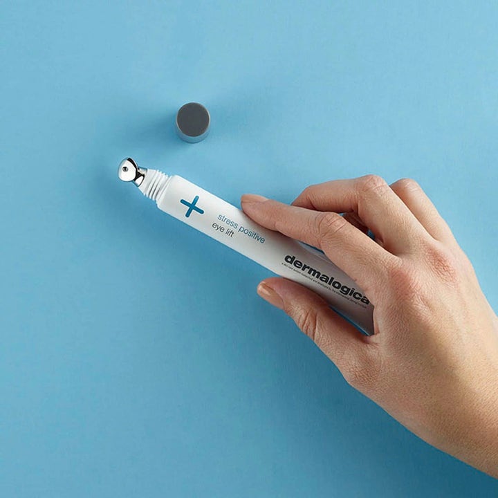 Dermalogica Stress Positive Eye Lift ögonkräm som dämpar svullnad i vit tub med kylande metallapplikator i en hand