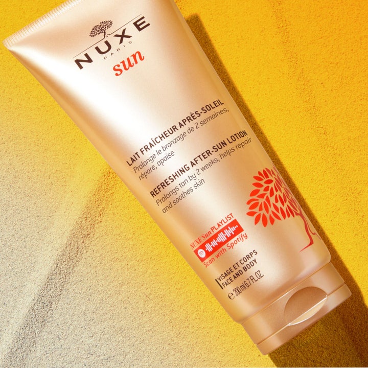 Nuxe Sun Refreshing After Sun Lotion 200 ml i tub på sand som ger 24h hydrating och hjälper till att behålla solbrännan.