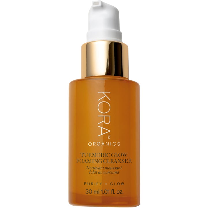 Kora Organics Turmeric Glow Foaming Cleanser 30 ml ger lyster i en bärnstensfärgad flaska med gulddetaljer och vit pump