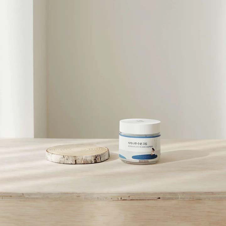 Round Lab Birch Juice Moisturizing Cream 80 ml fuktgivande ansiktskräm björksaft i burk intill en björkskiva.
