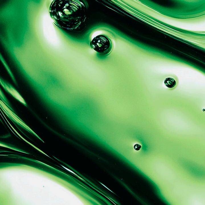 MANTLE The Body Retinoil 100 ml cellförnyande kroppsolja i en närbild på en glansig grön oljetextur med små bubblor.