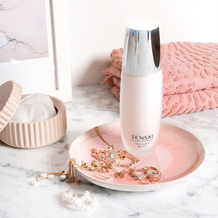Sensai Cellular Performance Emulsion II Moist fuktgivande ansiktskräm i frostat glas med silverlock på ett rosa fat.