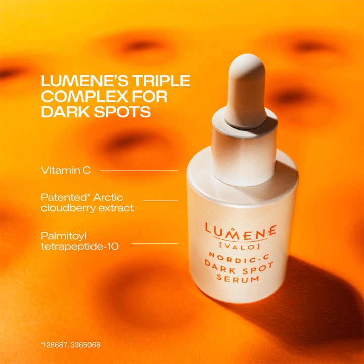 Lumene Dark Spot Serum 30 ml serum med Vitamin C mot mörka fläckar i vit flaska med pipett mot orange bakgrund