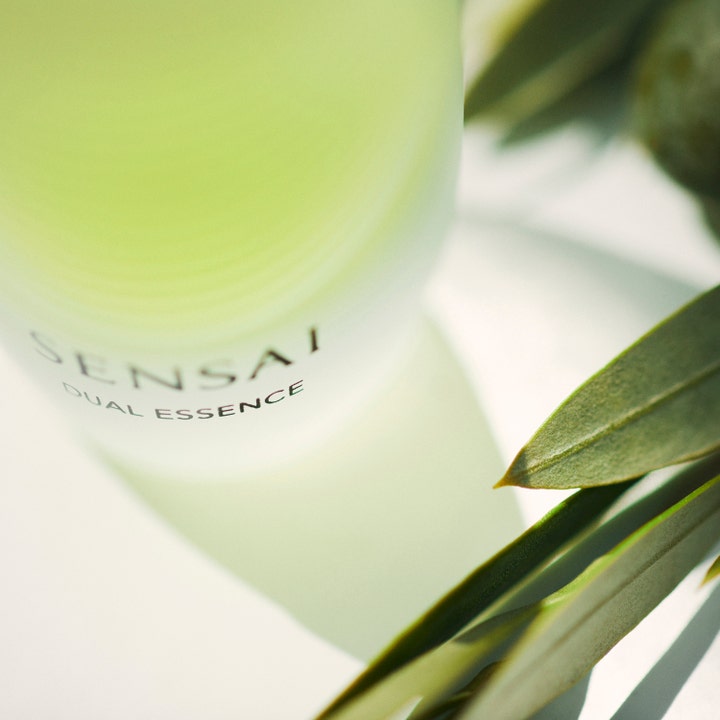 Sensai Dual Essence 30 ml dual återfuktande serum i frostad glasflaska skapar ansiktsglöd bland gröna blad