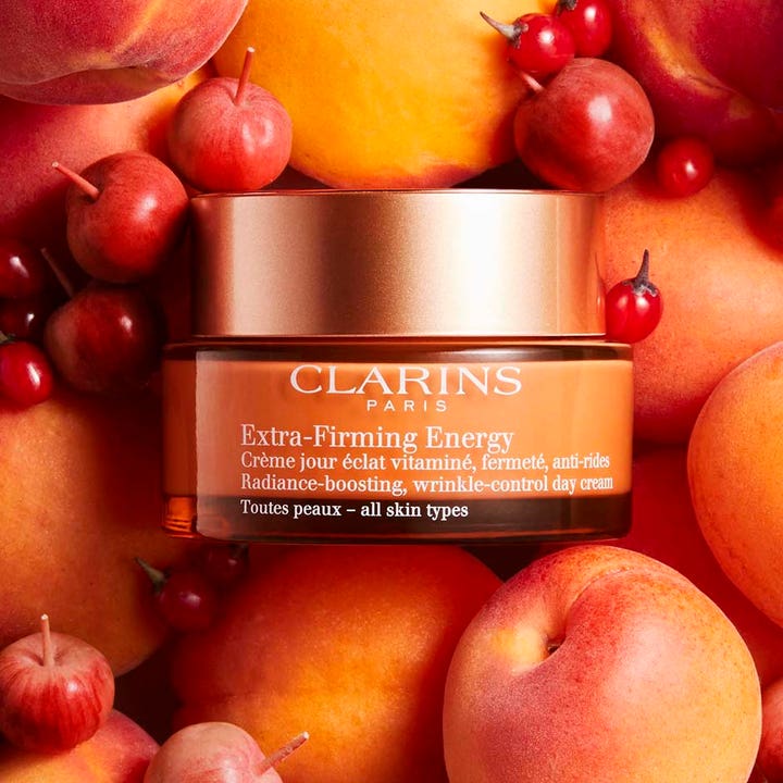 Clarins Extra-Firming Energy 50 ml anti-age kräm för utslätning av rynkor i orange glasburk omgiven av färsk frukt.