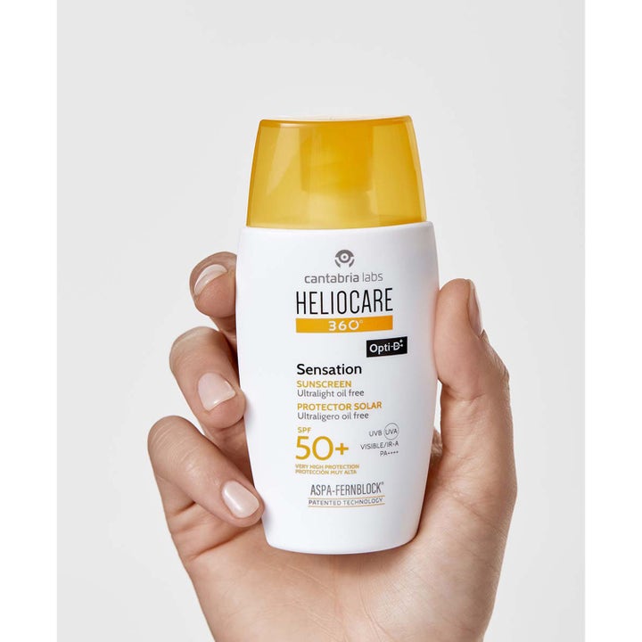 Heliocare Sensation 50 ml oljefri solkräm ansikte spf 50 i en vit flaska med gult lock som hålls i en hand.