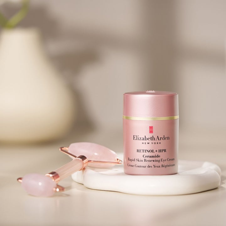 Elizabeth Arden Ceramide Retinol + Hpr Rapid Skin Renewing Eye Cream 15 ml i rosa flaska med en ansiktsroller.