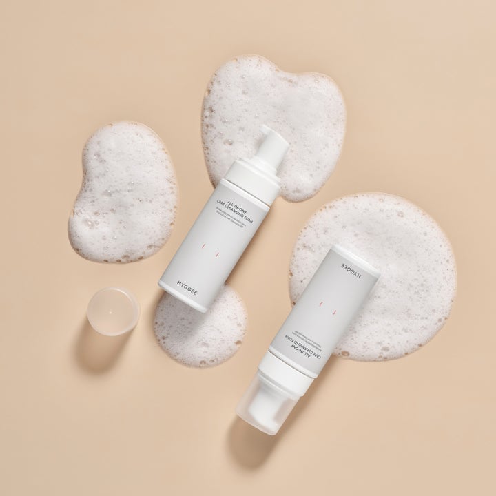 Hyggee All-In-One Care Cleansing Foam 150 ml rengöringsskum vita flaskor omgivna av fluffigt vitt skum