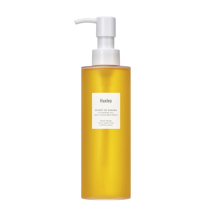 Huxley Secret of Sahara Cleansing Oil djuprengörande återfuktande olja i genomskinlig flaska med gul vätska och vit pump.