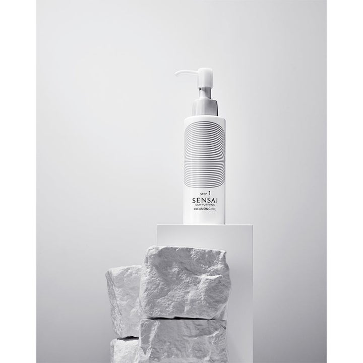 Sensai Moist Cleanse Ritual Cleansing Oil rengöringsolja i vit pumpflaska som ger ren hy placerad på vita stenar.