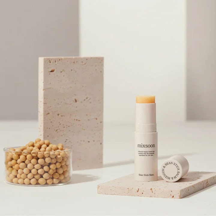 Mixsoon Bean Stick Balm 11.5 ml näringsbalsam ger fukt i ett smidigt fuktstick bredvid en skål med sojabönor.