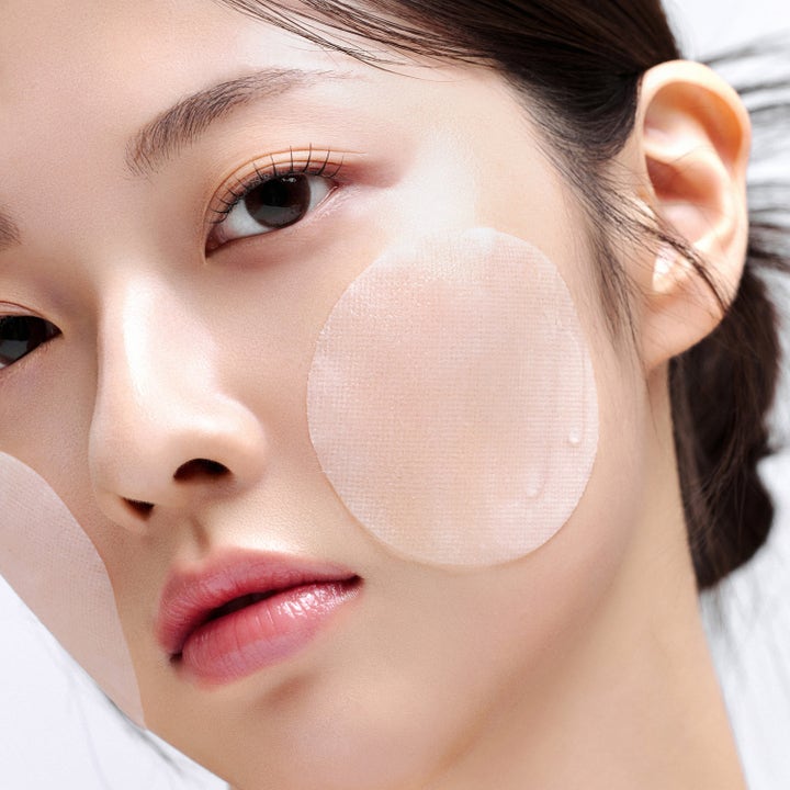 House of Hur Brightening Skin Prep Essence Pad 140 ml ger lyster med runda ark på modellens kinder.