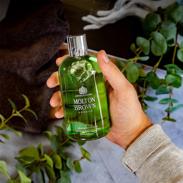 Molton Brown Infusing Eucalyptus Bath & Shower Gel 300 ml lyxig duschgel aromatisk i grön flaska som hålls i en hand