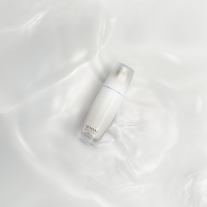 Sensai Absolute Silk Micro Essence-In-Lotion 125 ml fuktboostande hudvårdsessence i vit flaska på silkig bakgrund