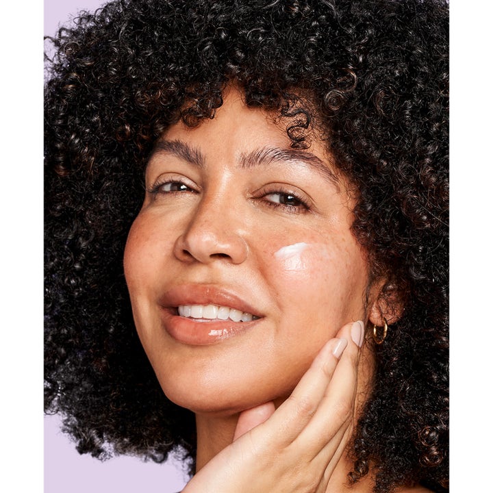 Exuviance Age Reverse + Rebuild-5 Cream 50 ml anti age dagkräm applicerad på en leende kvinnas kind
