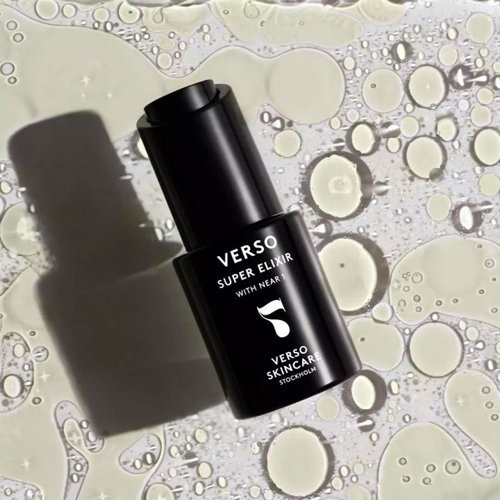 Verso N°7 Super Elixir 30 ml lystergivande ansiktsolja i svart flaska mot en bakgrund av klara oljedroppar.