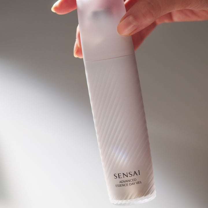 Sensai Advanced Essence Day Veil 40 ml lystergivande serum i en frostad vit flaska med räfflad yta i en hand