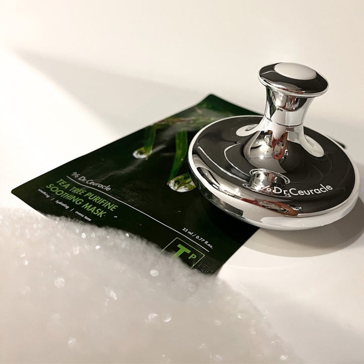 Dr. Ceuracle Cryo Tool 1 st hudvårdsverktyg för cryoterapi i blank silvermetall ovanpå en mörkgrön ansiktsmask.