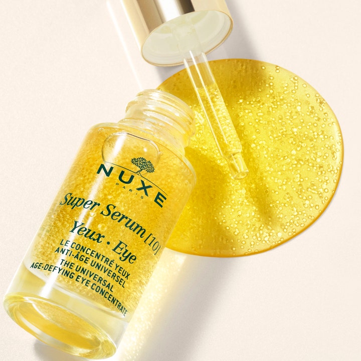 Nuxe Super Serum [10] Eye 15 ml anti-rynk ögonserum i glasflaska med guldlock och gyllene textur med mikropärlor