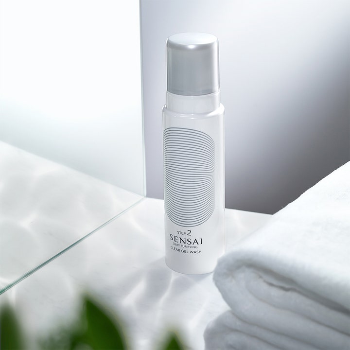 Sensai Silky Purifying Clear Gel Wash 145 ml clear gel rengöring i vit flaska med silverkork bredvid en vit handduk