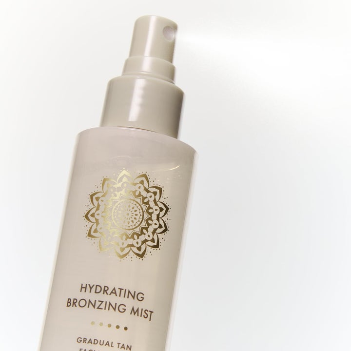 Bronza Hydrating Bronzing Mist 2 x 100 ml är en brun utan sol mist i beige sprayflaska med guldmönster.