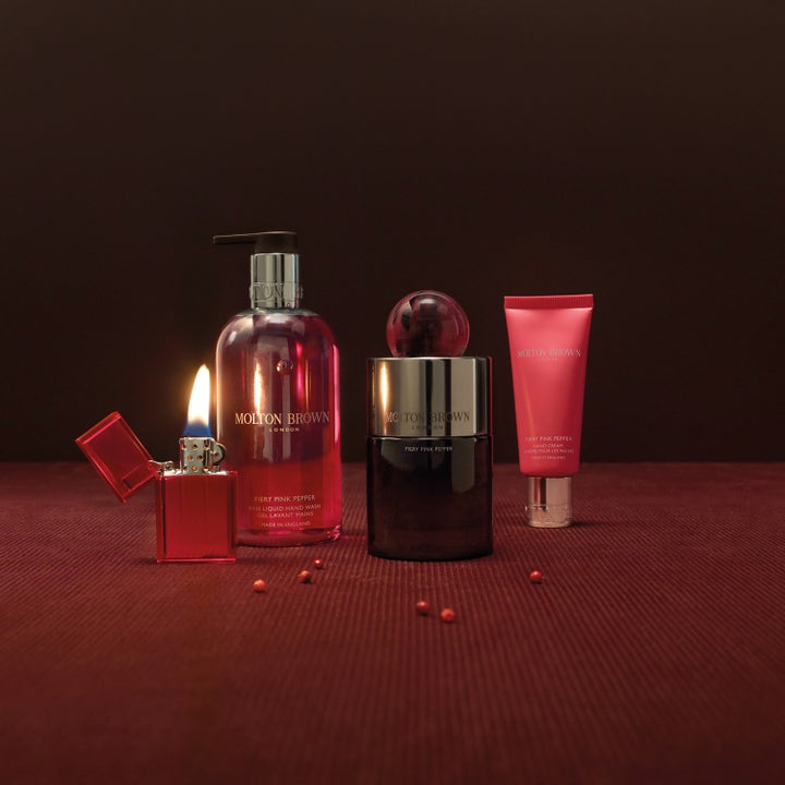 Molton Brown Fiery Pink Pepper handkräm 40 ml återfuktande kräm i rosa tub i miljö med pepparkorn och tändare