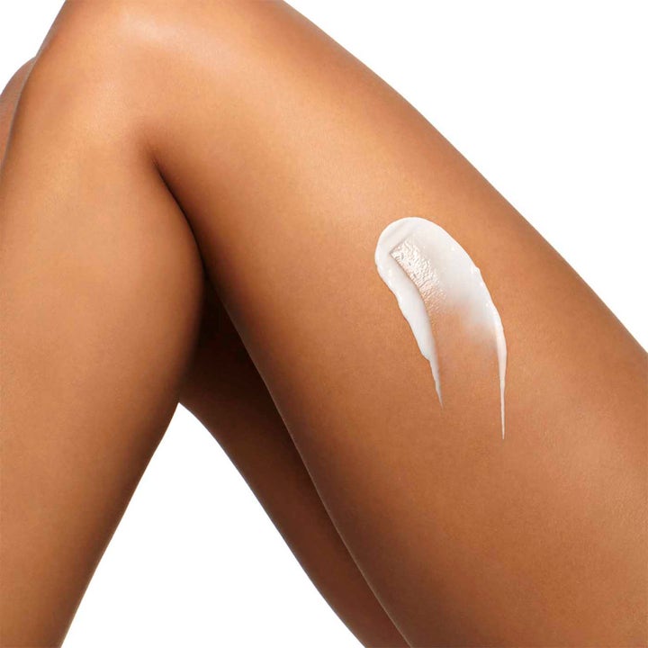 Clarins Hydrating Body-Smoothing Moisture Milk 400 ml återfuktande body lotion med krämig vit textur applicerad på ett ben