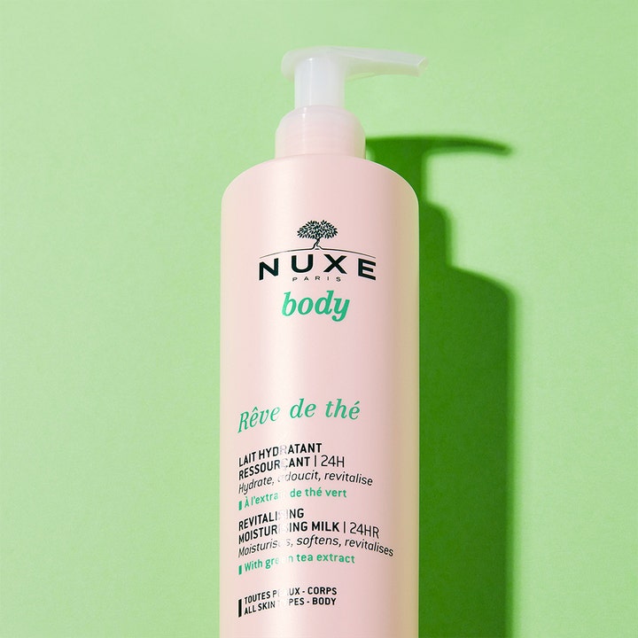 Nuxe Body Reve De Thé 400 ml återfuktande body lotion i ljusrosa flaska med vit pump mot en grön bakgrund