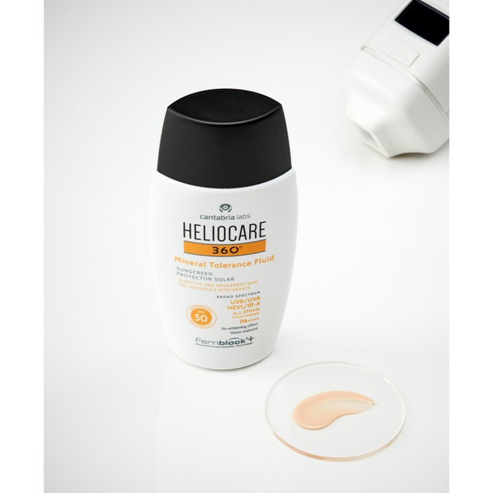Heliocare Mineral Tolerance Fluid 50 ml bredspektrum solskydd känslig hud i vit flaska med beige textur på glasplatta