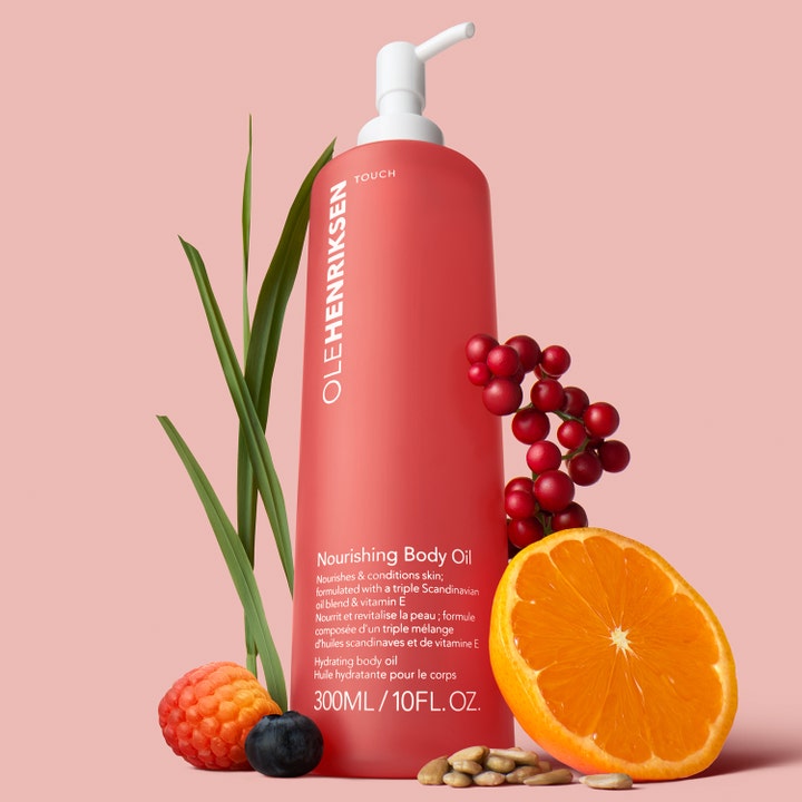 Ole Henriksen TOUCH Nourishing Body Oil 300 ml fuktgivande kroppsolja omgiven av bär och apelsin