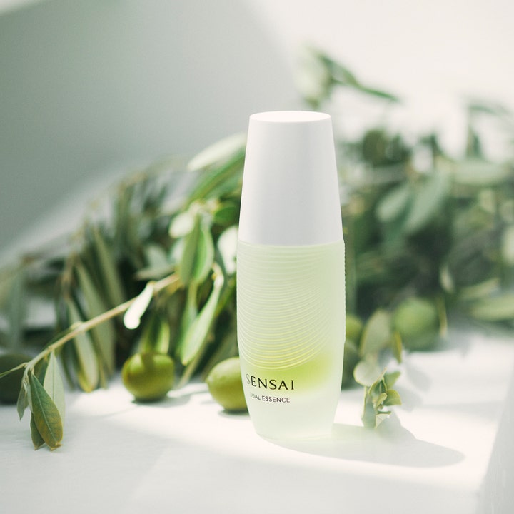 Sensai Dual Essence 30 ml anti age dual behandling för ansiktsglöd i vit flaska placerad vid olivkvistar.