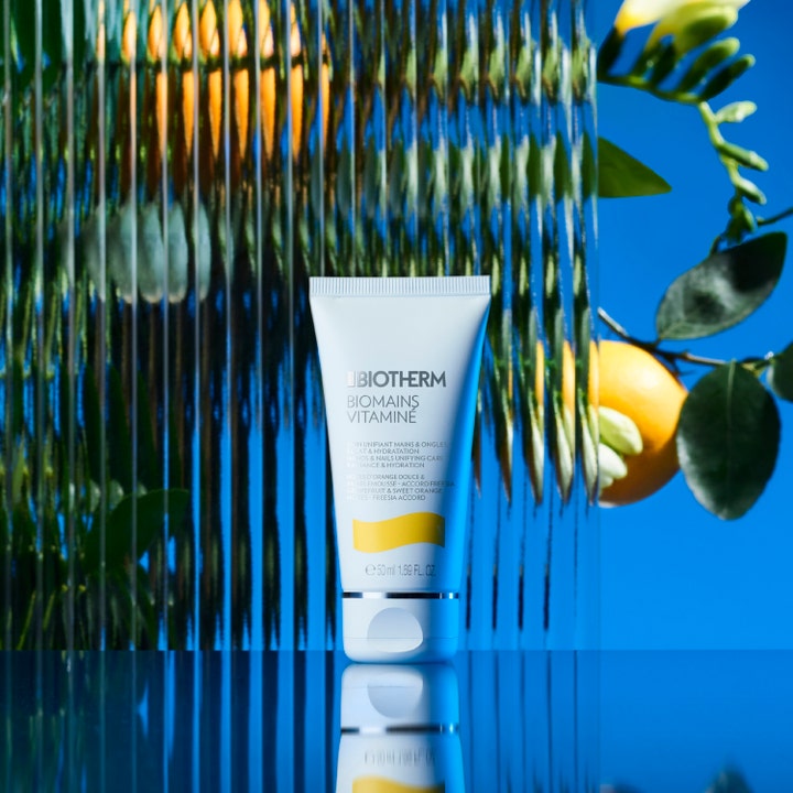 Biotherm Biomains Vitaminé 50 ml fuktgivande nagelvård och handkräm i vit tub framför citrus och blå bakgrund