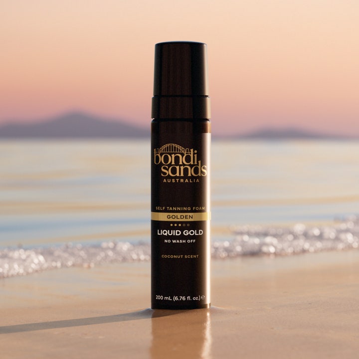 Bondi Sands Liquid Gold 200 ml australisk brun utan sol mousse i svart pumpflaska på en strand vid solnedgång.