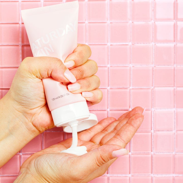 Saturday Skin Rise + Shine Gentle Cleanser 120 ml ansiktsrengöring som kläms ur rosa tub ner i en hand