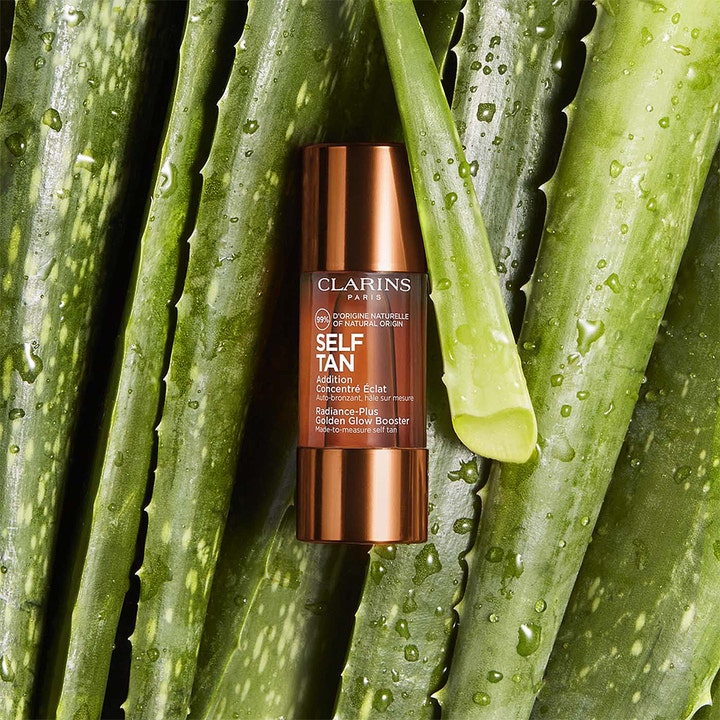 Clarins Radiance-Plus Golden Glow Booster Face 15 ml ger naturlig solkysst hy i flaska på aloe vera-blad.