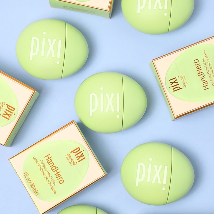 Pixi Hand Hero 30 ml närande handkräm i runda gröna behållare och askar mot blå bakgrund.