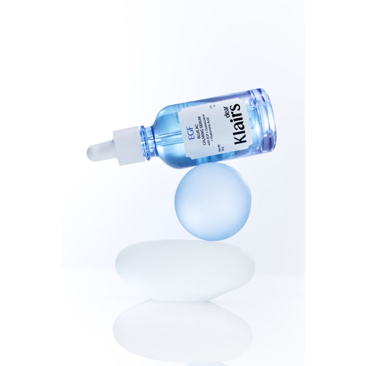 Klairs EGF Blue AC Calming Serum 50 ml ger lugnande hudvård i blå glasflaska balanserad på en rund frostad sfär.