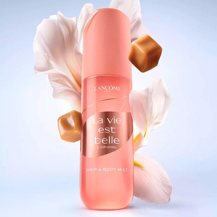 Lancôme La Vie est Belle Hair And Body Mist 100 ml i rosa flaska omgiven av vita blomblad och kola