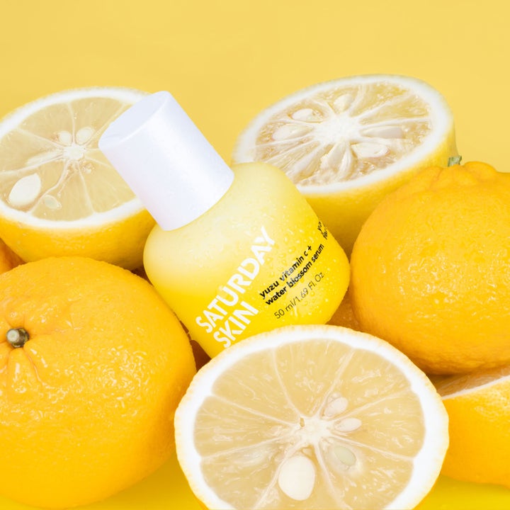 Saturday Skin Yuzu Vitamin C + Water Blossom Serum 50 ml ger lyster i en gul flaska omgiven av färska yuzufrukter.