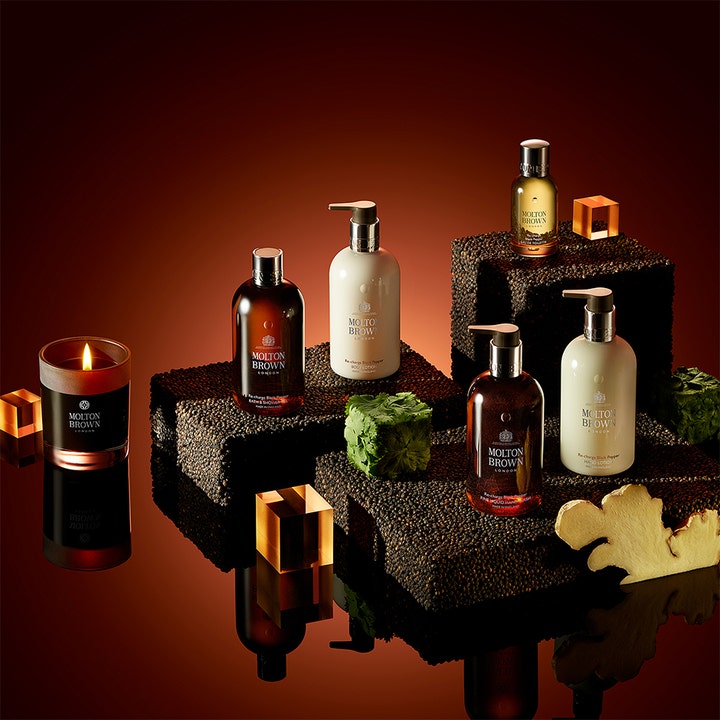 Molton Brown Black Peppercorn Body Lotion 300 ml återfuktande kroppslotion för män i stämningsfull miljö med tänt ljus.
