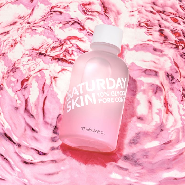 Saturday Skin Pore Clarifying Toner 125 ml med glykolsyra i rosa frostad flaska på en krusig rosa vattenyta