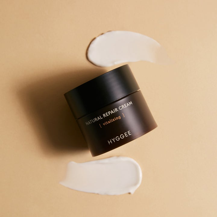 Hyggee Natural Repair Cream 50 ml barriärkräm för ansiktet i mörk burk med vita texturprover på beige bas