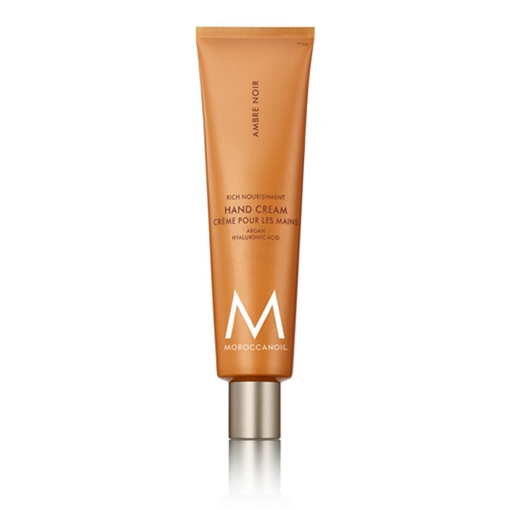 Moroccanoil handkräm Ambre Noir med hyaluronsyra för torr hud i en bärnstensfärgad tub med silverlock.