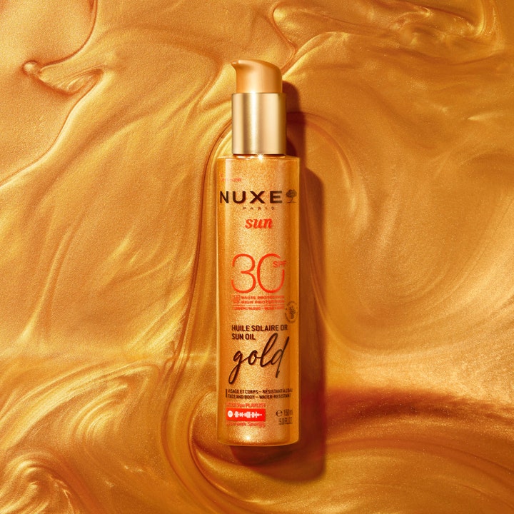 Nuxe Sun Tanning Oil Gold SPF30 150 ml guld solbränningsolja på en skimrande bakgrund av flytande guld.