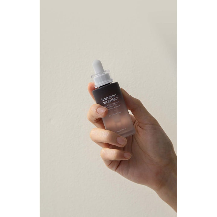 haruharu wonder Black Rice Hyaluronic Botanical 2GF Ampoule 30 ml svart ris ampull i frostad glasflaska som hålls i en hand